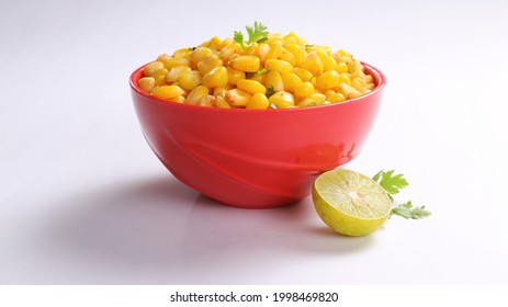 Sweet Corn Chat Or Steamed Yellow Sweet Corn, Chat Masala And Lemon, Served In Red Bowl. Indian Chat Or Snack. Sweetcorn Or Sweet Corn On Isolated White Background