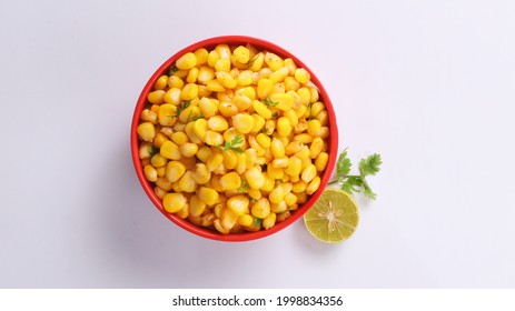 Sweet Corn Chat Or Steamed Yellow Sweet Corn, Chat Masala And Lemon, Served In Red Bowl. Indian Chat Or Snack.Top View Sweetcorn Or Sweet Corn On Isolated White Background