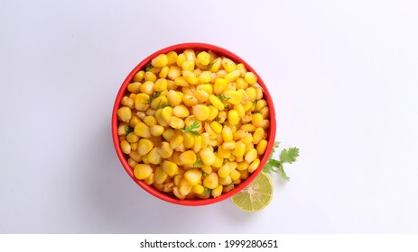 Sweet Corn Chat Or Steamed Yellow Sweet Corn, Chat Masala And Lemon, Served In Red Bowl. Indian Chat Or Snack. Top View Sweetcorn Or Sweet Corn On Isolated White Background