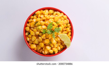 Sweet Corn Chat Or Steamed Yellow Sweet Corn, Chat Masala And Lemon, Served In Red Bowl. Indian Chat Or Snack. Top View Sweetcorn Or Sweet Corn On Isolated White Background