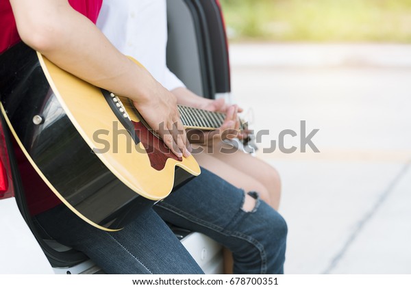 Sweet\
couple playing guitar on the car,summer\
holiday.
