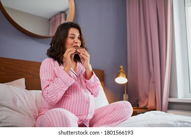 sweet craving during pregnancy concept, pregnant woman with chocolate on bed. relaxed future mom eating chocolate bar, resting at home - Powered by Shutterstock