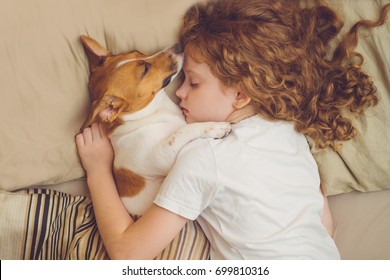 Süße, lockige Mädchen und Jakobsmuschel Hund schläft in der Nacht.
