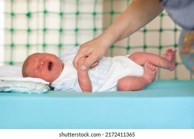 Sweet And Cute Small Little Newborn Baby Cry Strongly While Caring Mother Tries To Calm And Comfort Her By Holding Her Little Hand. Stomach Cramps