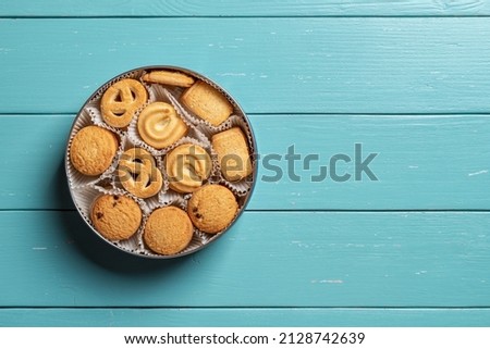 Sweet danish butter biscuits in an open tin on a turquoise wooden tabletop. Assorted crispy shortbread cookies for breakfast. Baked pastry. Sweet food and calories concepts. Copy space. Top view.