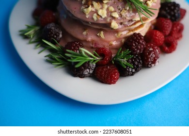 sweet delicious fragrant pink cupcakes in the shape of a heart and round with pink icing on top and decorated with blackberry raspberries and a sprig of rosemary on a blue background. for signage menu - Powered by Shutterstock