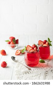 Sweet dessert jelly pudding with strawberries in glass jar on white background