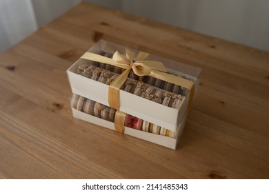 Sweet Dessert Macaroons In A Box Decorated With A Ribbon, On A Wooden Table.