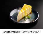 Sweet dessert on a plate on a black background. Classic cheesecake with yellow lemon syrup. Copy space.