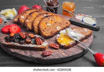 Sweet dessert sandwiches crostini with lemon jam, plums jam, nuts pecans, hazelnuts, almonds, strawberries, rye bread for sandwiches, butter, cutting board on black wooden background - Powered by Shutterstock