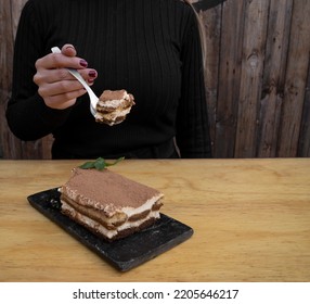 Sweet Desserts. Closeup View Of A Woman's Hand Holding A Spoon With A Slice Of Italian Dish Tiramisu Cake.