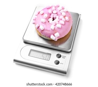 Sweet doughnut on digital kitchen scales, isolated on white