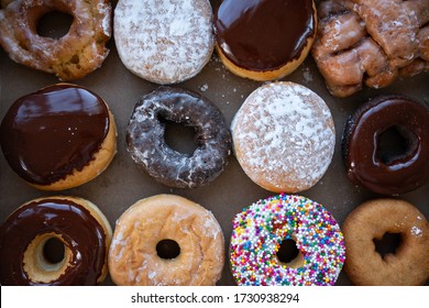 Sweet Dozen Of Donuts In Paper Box. Picture Of Donut Box With One Dozen Assorted Fresh Baked Donuts- Chocolate Glazed, Sprinkles, Boston Cream, Jelly, Sour Cream Glazed, Apple Fritter And Traditional.