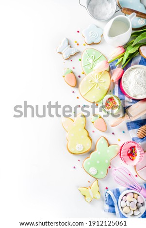 Sweet Easter baking cooking background with traditional bunny and egg cookies, sugar sprinkles, ingredients, utensils. White table background copy space layout