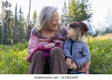 Sweet Family Moment As Aging Grandmother And Young Grandson Are Seen Looking At Each Other With Wide Happy Smile, Gran With Arm Around Grandchild.