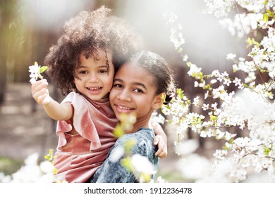 Sweet family portrait of two little sisters outdoors in springtime
