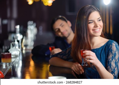 Sweet flirt. Smiling young woman delighted with a attention of a young man sitting near her at the bar
