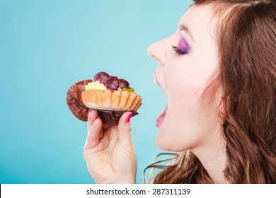 Sweet Food Indulging And Fattening Concept. Woman Face Profile Wide Open Mouth Eating Cake Cupcake Blue Background