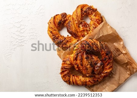 Sweet french soft pretzels or bretzels with puff pastry, almonds and custard cream. A type of baked dessert made from dough that is shaped into a knot. Street food, white background.