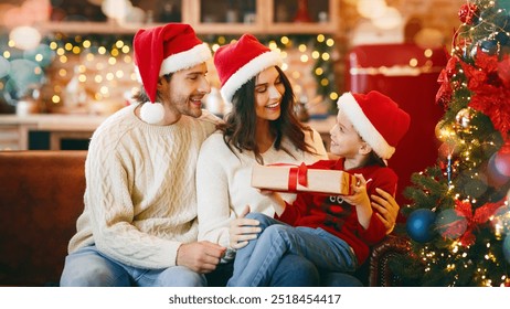 Sweet girl in santa hat asking parents permission to open xmas gift, sitting next to christmas tree at home together - Powered by Shutterstock