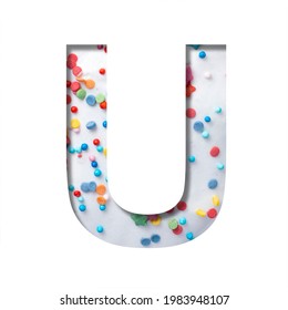 Sweet Glaze Font. The Letter U Cut Out Of Paper On The Background Of White Sweet Glaze With Colored Sprinkles. Set Of Decorative Holiday Or Birthday Fonts.