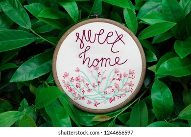 Sweet Home Embroidery In A Wooden Hoop In Green Leaves In The Background