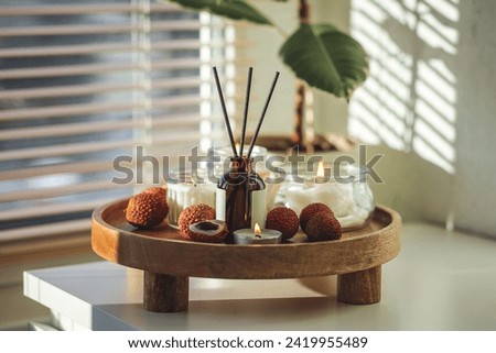 Sweet home perfume with tropical exotic fruits. Reed diffuser on wooden tray in a bedroom. Burning candles, atmosphere of relaxation, detention, meditation. Oriental interior, Bali, Thai vibes