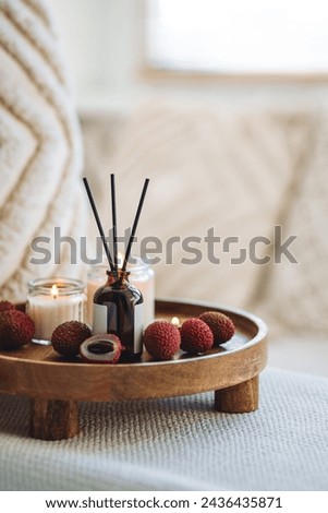 Sweet home perfume with tropical exotic fruits. Reed diffuser on wooden tray in a bedroom. Burning candles, atmosphere of relaxation, detention, meditation. Oriental interior, Bali, Thai vibes