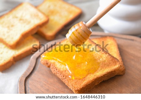 Sweet honey dripping on toasted bread on table