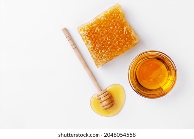 Vista superior de miel dulce y peine de miel sobre fondo blanco. miel orgánica saludable en un bol y cuentagotas de miel de madera. Dulce postre saludable.