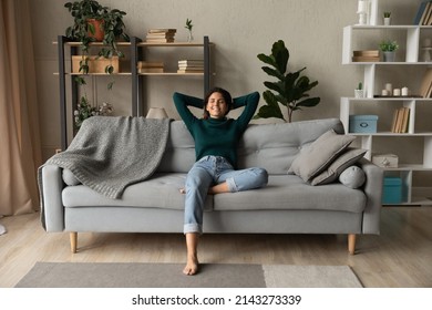 Sweet idleness. Lazy young hispanic lady sit in relaxed pose on big comfy sofa at living room interior breath air dream imagine. Successful female new flat apartment buyer rest at home feel pleasure - Shutterstock ID 2143273339