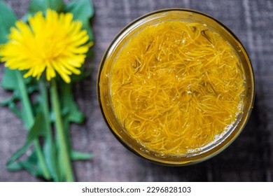 Sweet jam in glass jar jam from ripe yellow petals of dandelion flowers, orange, lemon and sugar, top view, close up. Dandelion famous medicinal plant - Shutterstock ID 2296828103