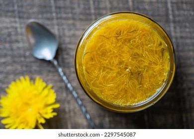 Sweet jam in glass jar jam from ripe yellow petals of dandelion flowers, orange, lemon and sugar, top view, close up. Dandelion famous medicinal plant - Shutterstock ID 2297545087