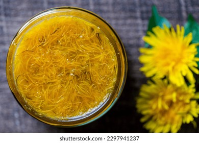 Sweet jam in glass jar jam from ripe yellow petals of dandelion flowers, orange, lemon and sugar, top view, close up. Dandelion famous medicinal plant - Shutterstock ID 2297941237