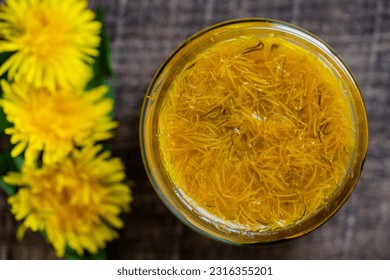 Sweet jam in glass jar jam from ripe yellow petals of dandelion flowers, orange, lemon and sugar, top view, close up. Dandelion famous medicinal plant - Shutterstock ID 2316355201