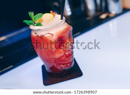 Sweet juicy Cherry Cocktail drink in skull glass with burnt lime on top on bar counter . Close-up Top view . Trendy stylish edit . Copy paste space and luxury concept service barman in nightclub