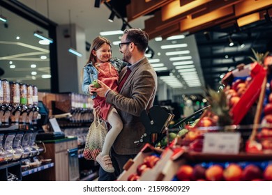 Sweet Kid Helping Her Dad Shop For Fruits At The Supermarket.