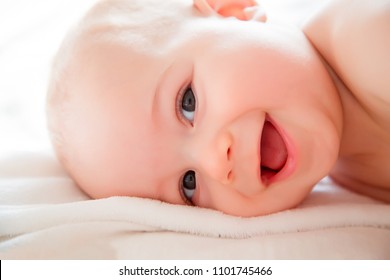 Sweet Little Boy With Friendly Attitude Play In White Sunny Bedroom. Close-up Portrait Of A Beautiful Sleeping Baby Boy. Newborn, Childhood Theme.Family Morning At Home. New Born Kid During Tummy Time