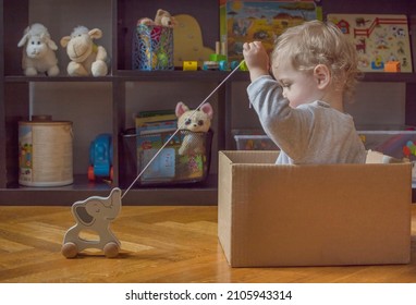 süßer kleiner Junge, der sich zu Hause amüsiert und mit bunten Spielzeugen auf dem Boden spielt. Aktivitäten im Innenbereich für Kinder