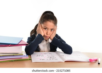 sweet little female latin child studying on desk looking bored and under stress with a tired face expression in children education and back to school concept isolated on white background