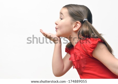 Sweet little girl blowing kisses, wearing a red t-shirt with hearts.