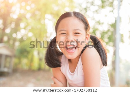 sweet little girl outdoors in the wind. portrait of attractive little student girl with beautiful. happy smiling child looking at camera - close-up, outdoors. jolly nature childhood leisure concept.