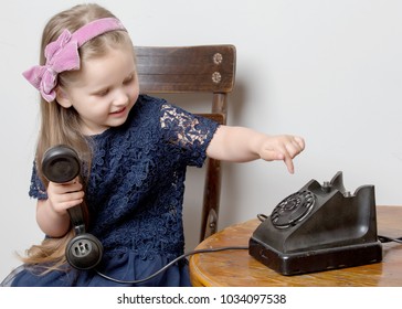 A Sweet Little Girl Is Ringing On The Old Phone. The Concept Of A Happy Childhood, Retro Style, Old Things Of The Fifties Of Last Century.