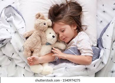 Sweet Little Girl Sleeping With Toys In Crib. Close Up Portrait Of Infant Sleeping In Cot. Beautiful Toddler Sleeping With Toy Bear And Dog, Tired Baby Relax. Sweet Bedtime And Childhood Concept..