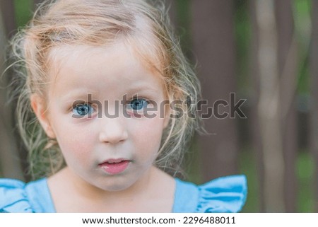 Sweet little girl, three years old. The girl smiles, looks into the camera. blonde girl with Blue eyes.Concept: summer, holidays, happy childhood.Little girl looks at the camera