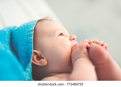 sweet lovely newborn baby girl eating foot, smooth skin, play in the bathroom turquoise towel  - Shutterstock ID 771484735