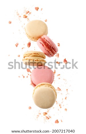 Sweet macaroons macarons with crumbs falling flying isolated on  white background. French cookies with vanilla, raspberry and strawberry. Pastry shop card 