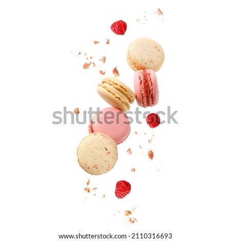 Sweet macaroons macarons with raspberry berries and crumbs flying isolated on  white background. French cookies with vanilla, raspberry and strawberry falling. Pastry shop card 