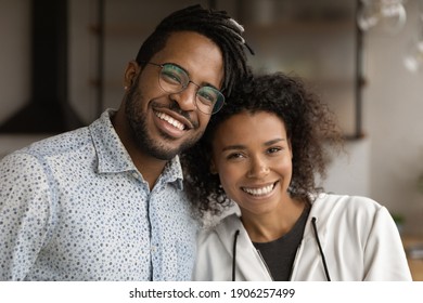 Sweet moment. Headshot family portrait of loving millennial black couple husband and wife hugging with warmth looking at camera demonstrating happy white smiles. Close relationship. Strong marriage