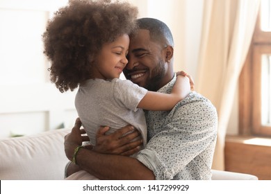 Sweet Moments Of Fatherhood Concept, Happy African Father Hold Embrace Cute Little Child Daughter, Smiling Black Family Mixed Race Daddy And Small Kid Hugging Cuddling Enjoying Time Together At Home